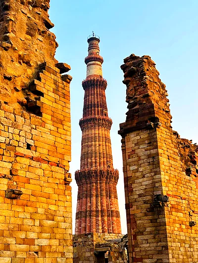Golden Qutub Minar rising between ancient ruins, Delhi