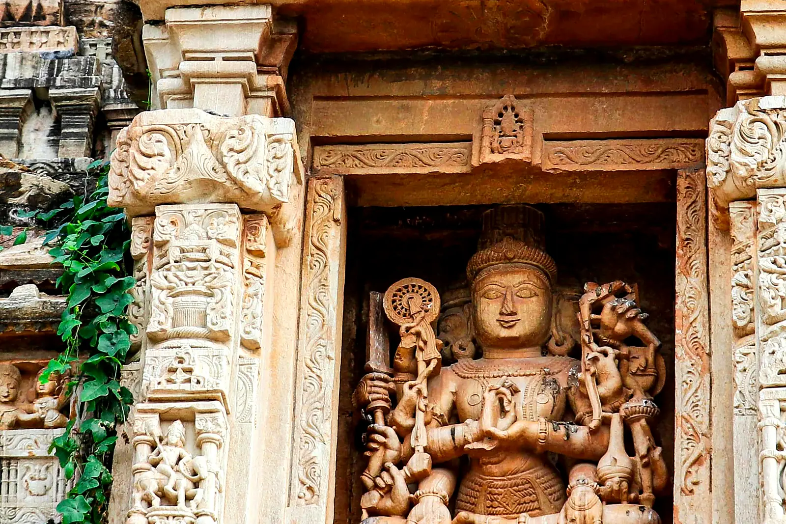 Intricately carved stone deity in a temple niche