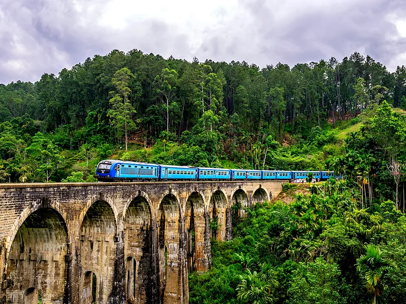 Blue train crossing the Nine Arch Bridge through jungle near Ella, Sri Lanka