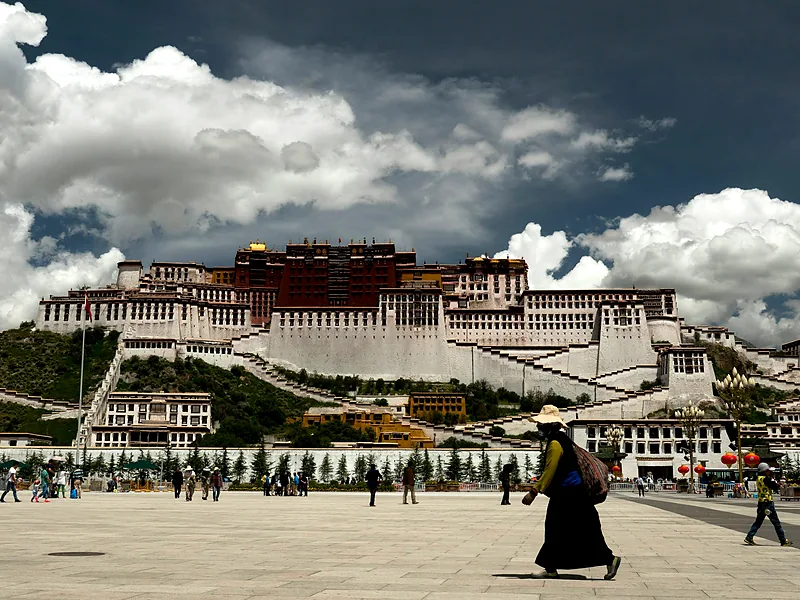 The Potala Palace rising above its square in Lhasa under dramatic clouds